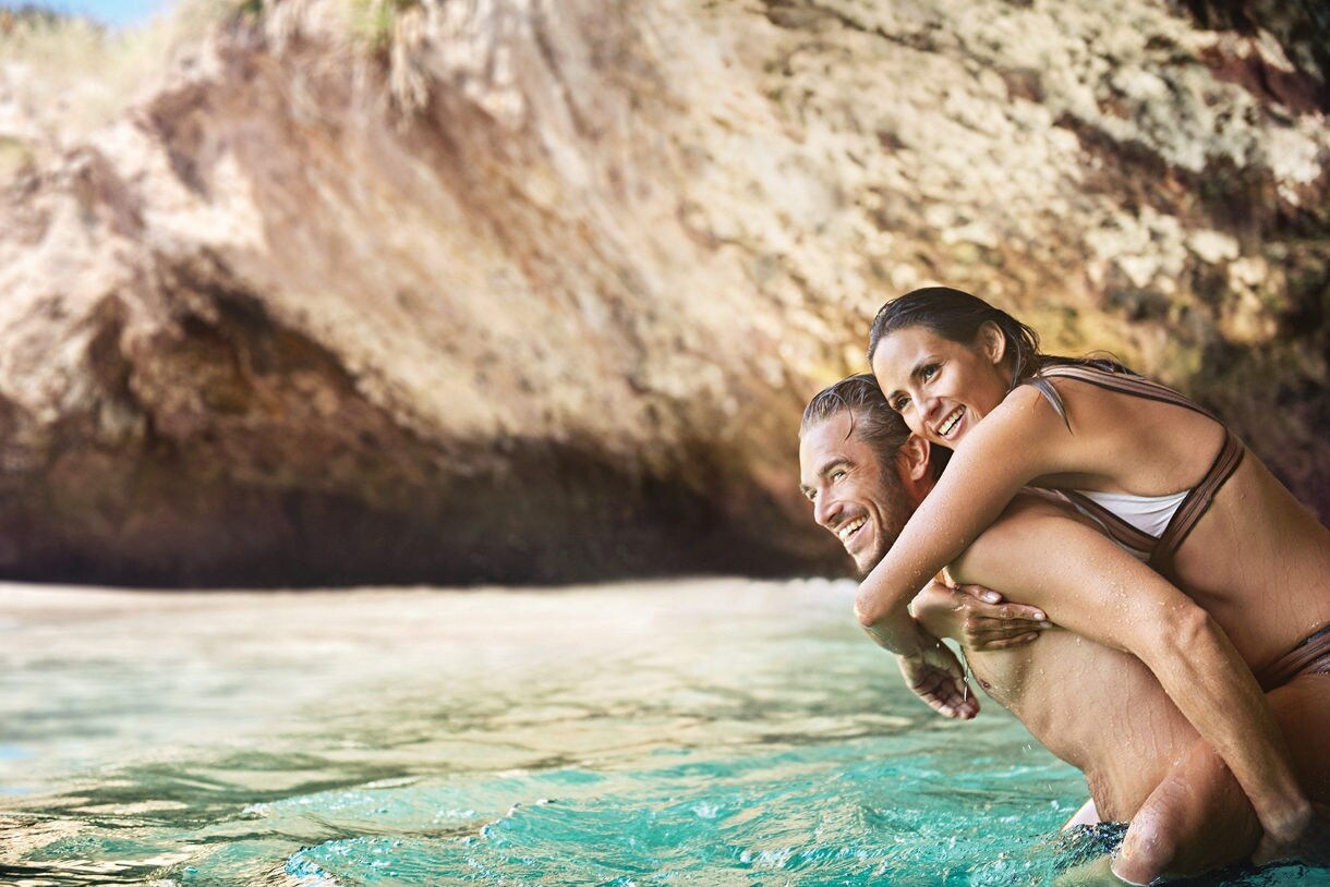 A couple enjoying crystal-clear turquoise waters at a tropical beach destination, perfect for escaping winter weather.