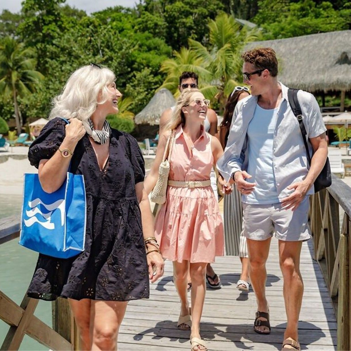 A happy family walking down a dock in the Caribbean, smiling and laughing.