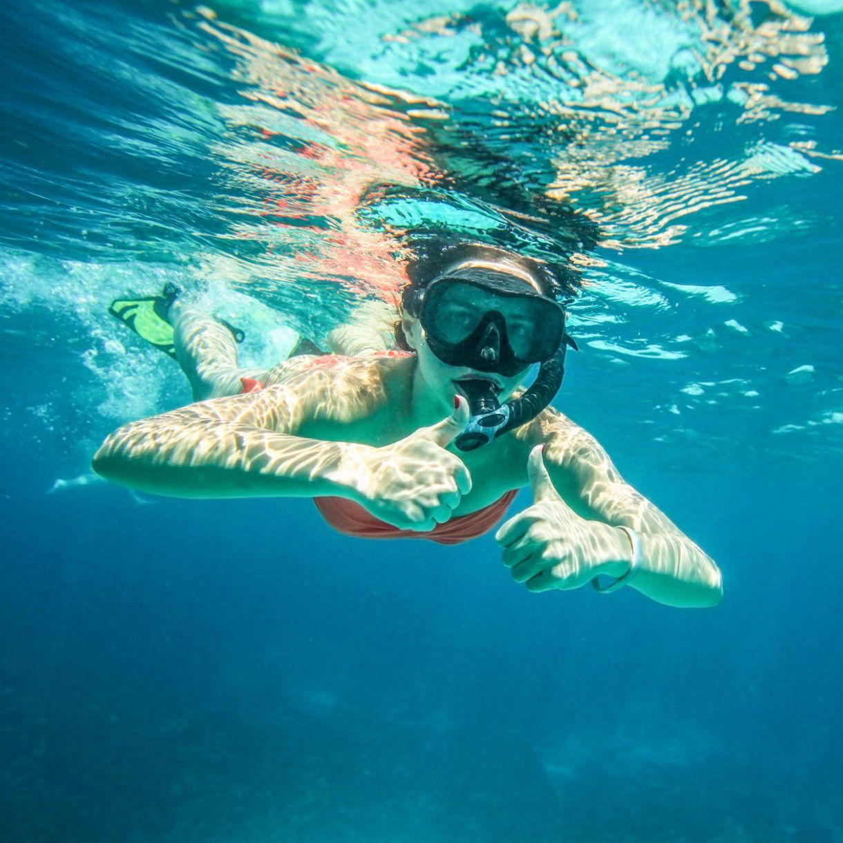 Young woman snorkel, holding two thumbs up
