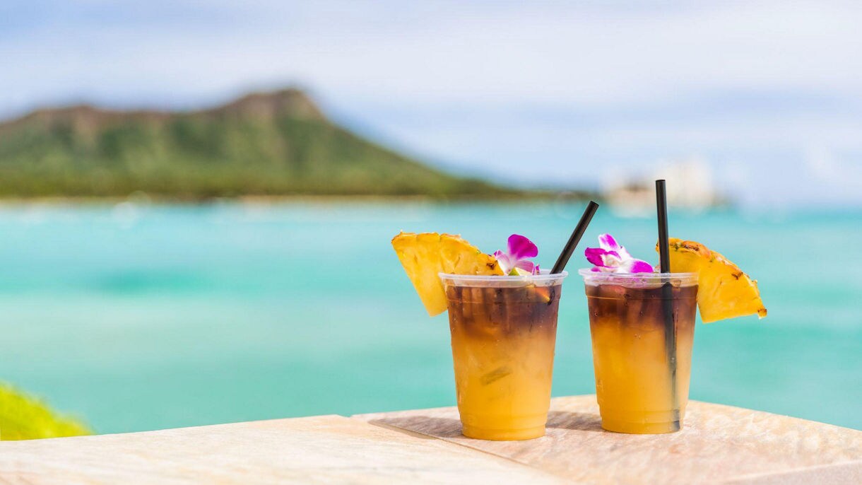 Two tropical cocktails with pineapple slices and flowers on a beachside table at VIVO Beach Club.