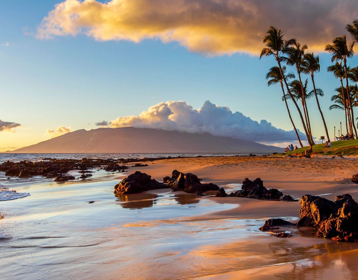 The sunset creates a warm glow on a beach in Maui