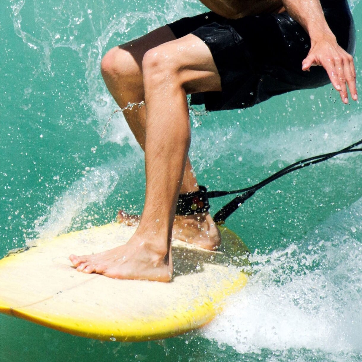 A young surfer in a wetsuit smiles while riding a gentle wave under the bright Puerto Rican sun. 