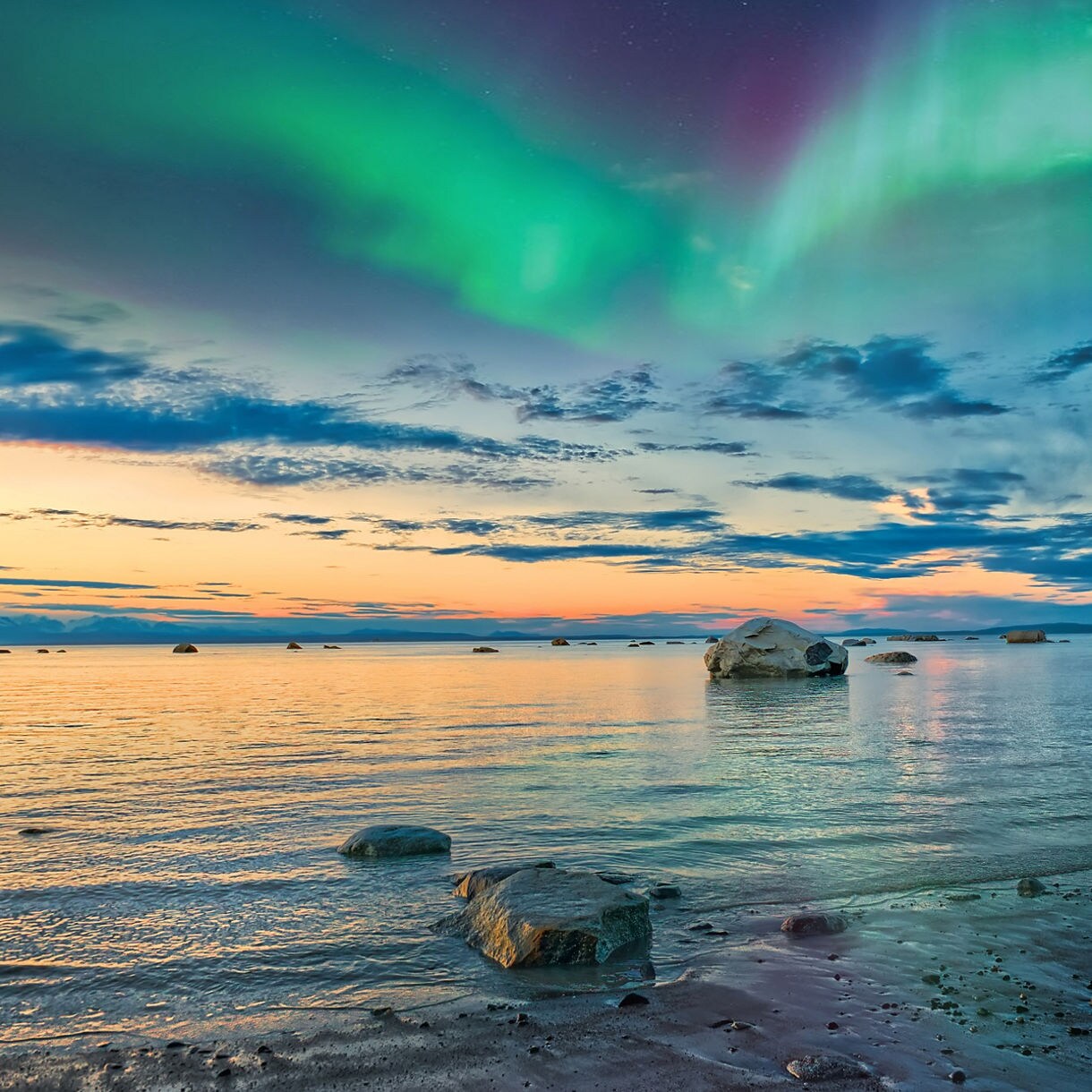 A stunning aurora borealis illuminates the night sky above the tranquil sea in Norway, creating a breathtaking natural spectacle.