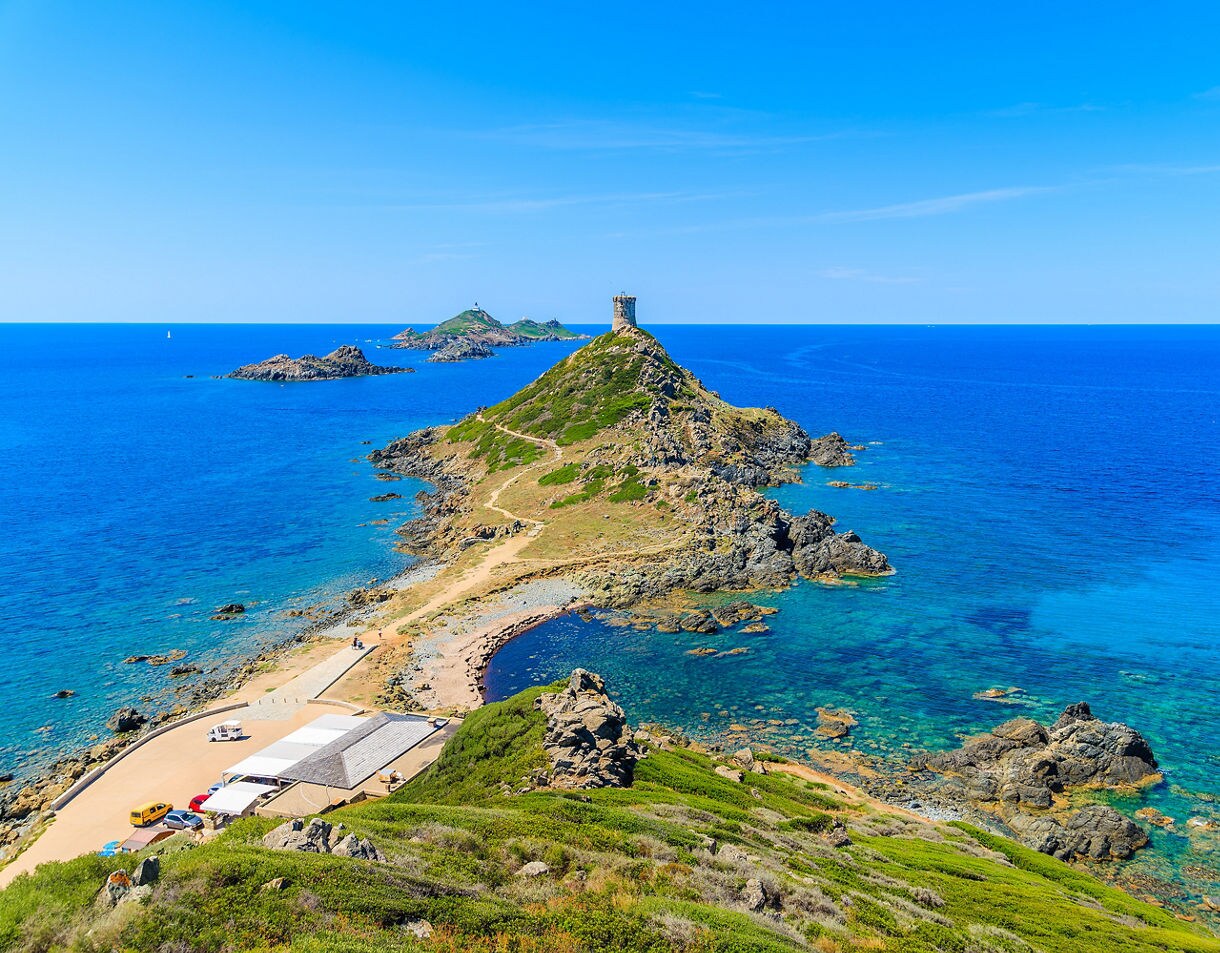 Scenic view of Parata Tower on a rocky peninsula near Ajaccio, France, surrounded by turquoise waters and small offshore islands under a clear sky.