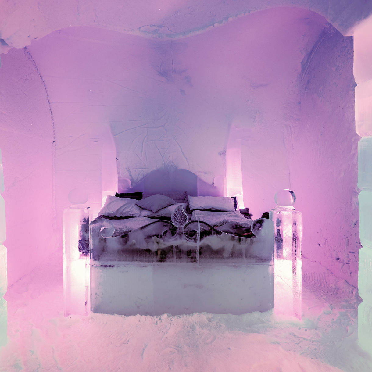 Bed made of ice blocks and furs inside a glowing purple-lit ice hotel room in Alta, Norway.