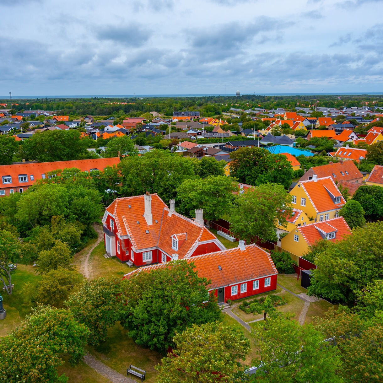 Aerial view of Skagen, Denmark, with red and yellow houses surrounded by green trees and orange tiled roofs.
