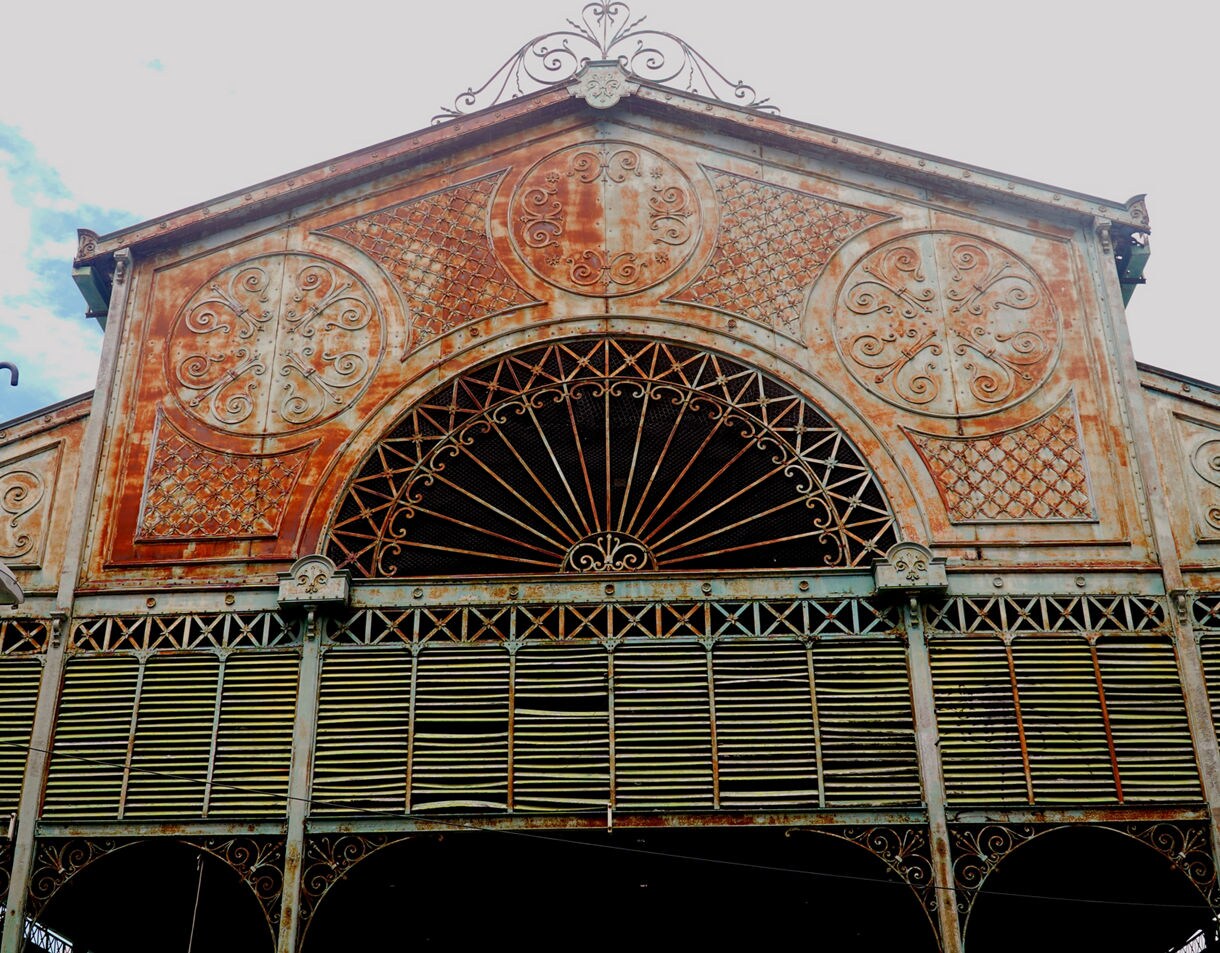 Close-up of an aged Art Nouveau building façade with intricate iron designs, circular patterns and weathered metal panels.