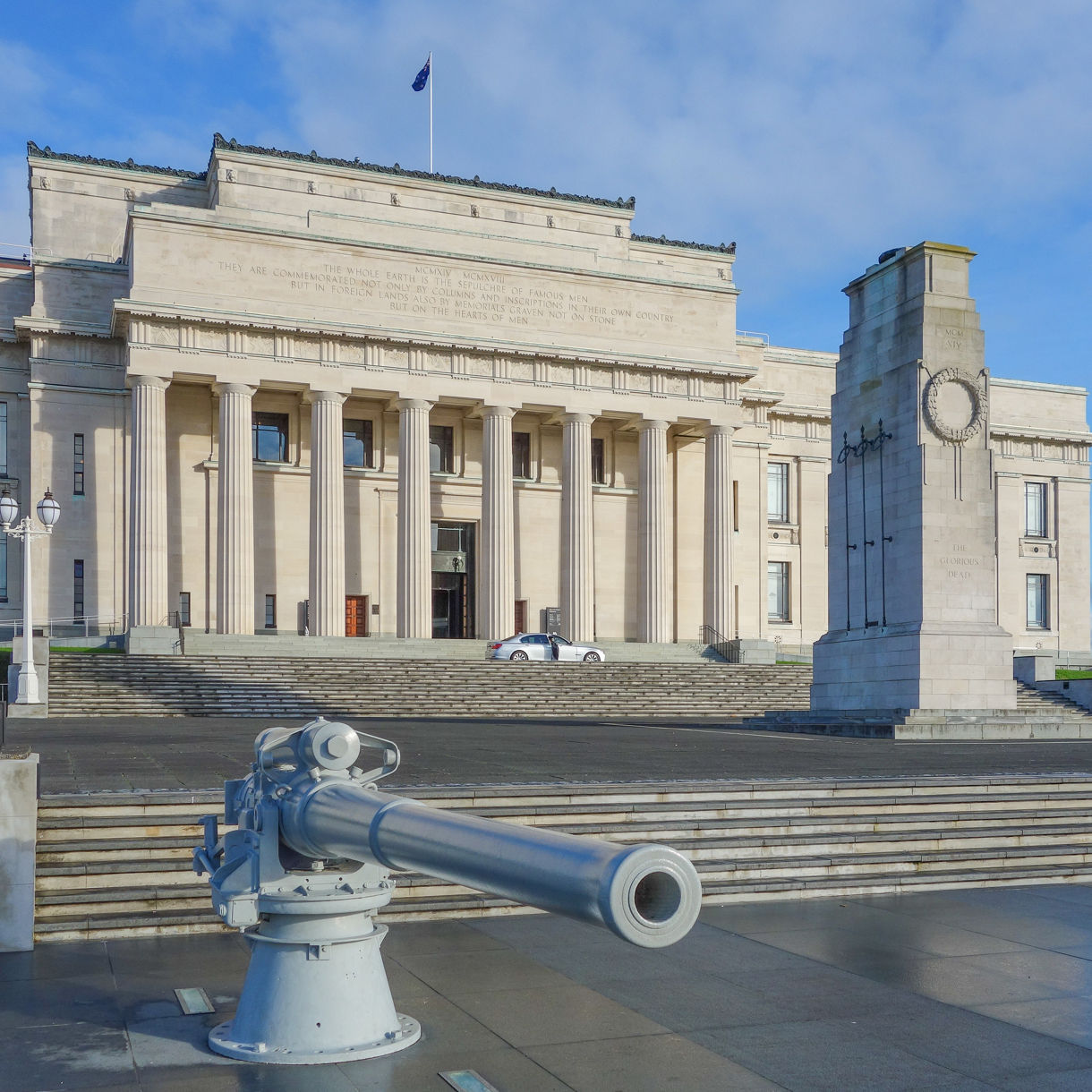 Front view of the Auckland War Memorial Museum, featuring neoclassical architecture with columns, a cenotaph and a historic cannon in the foreground.