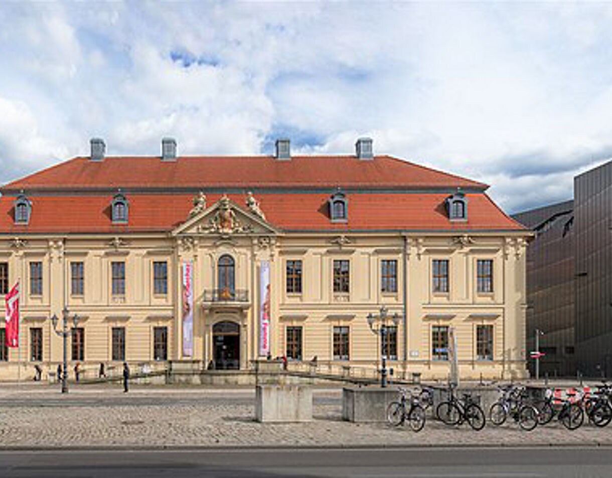 Exterior of the Jewish Museum in Berlin showing the historic baroque Kollegienhaus with red roof alongside Daniel Libeskind’s angular modern steel addition.