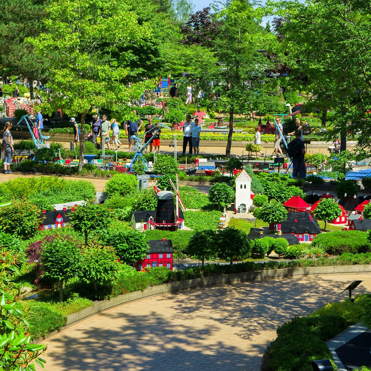 Miniature Lego-built town with houses, windmills and trees surrounded by visitors at Legoland Billund.