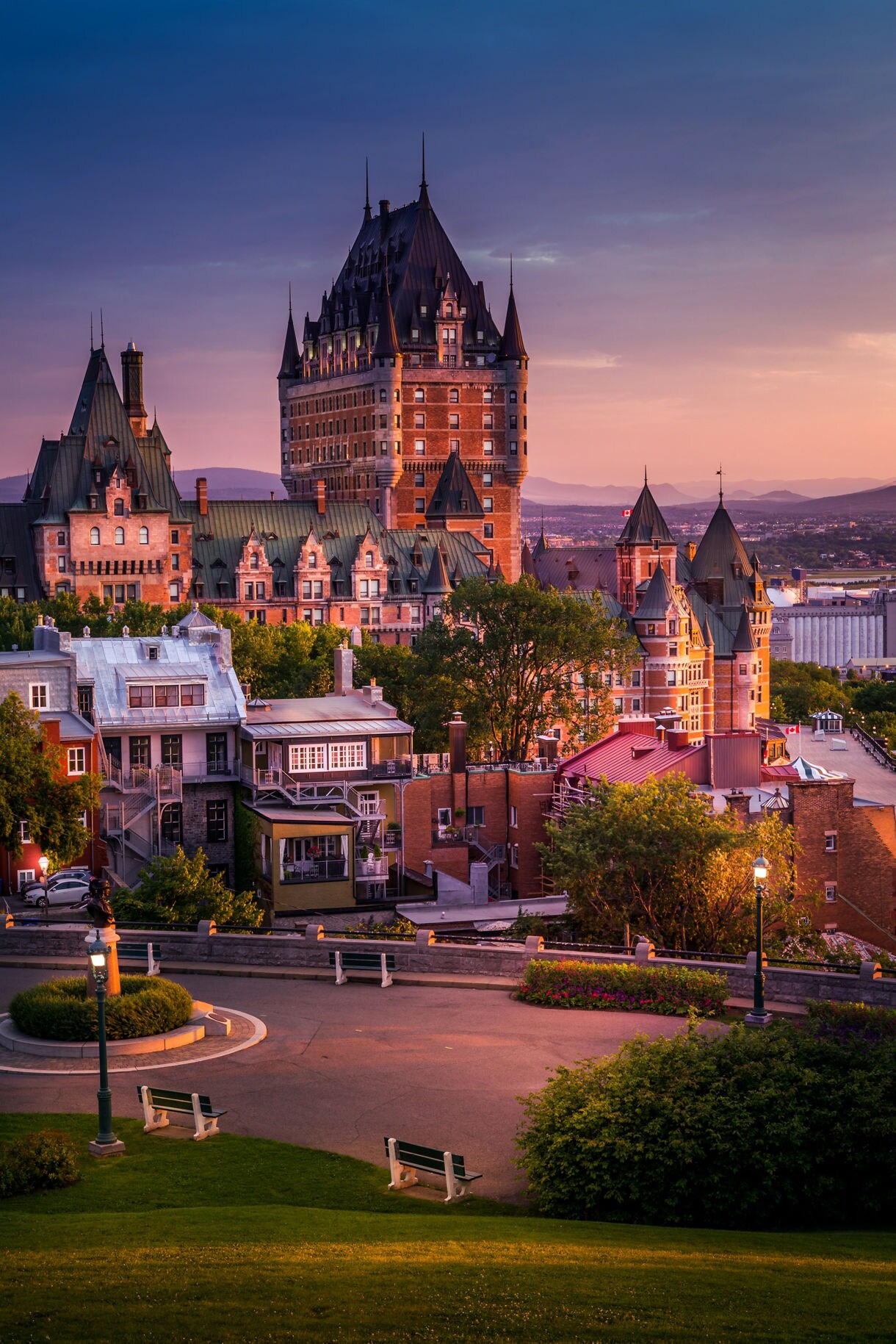View of Québec City at sunset featuring Château Frontenac’s grand turrets and surrounding historic buildings lit by warm evening light
