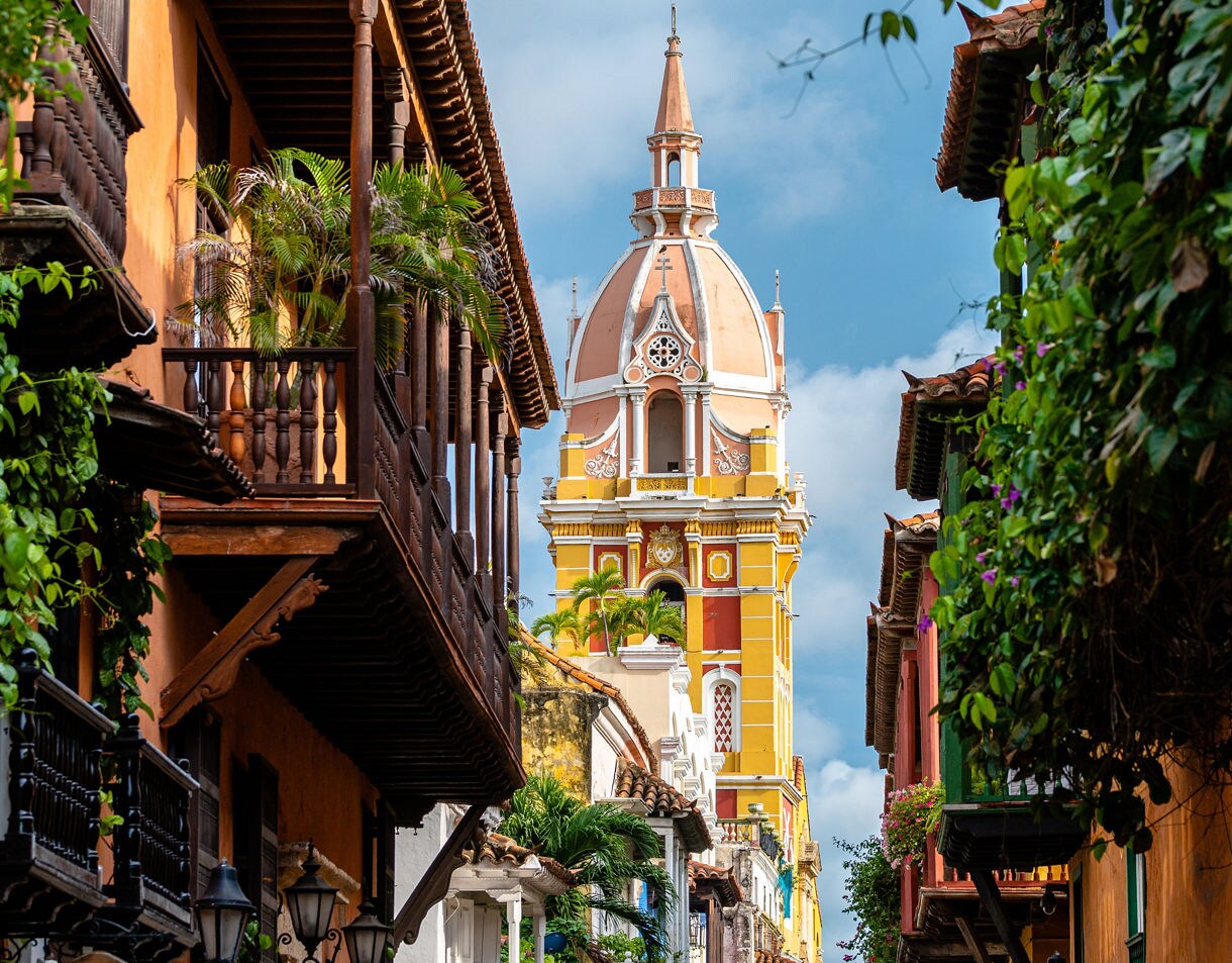 View of Cartagena Cathedral’s dome rising above narrow streets with vibrant colonial balconies and greenery.