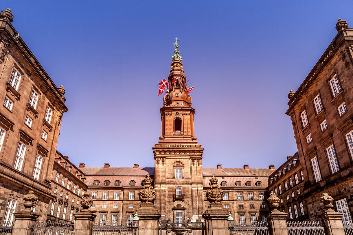 Front view of Christiansborg Palace in Copenhagen with its central tower flying Danish flags.
