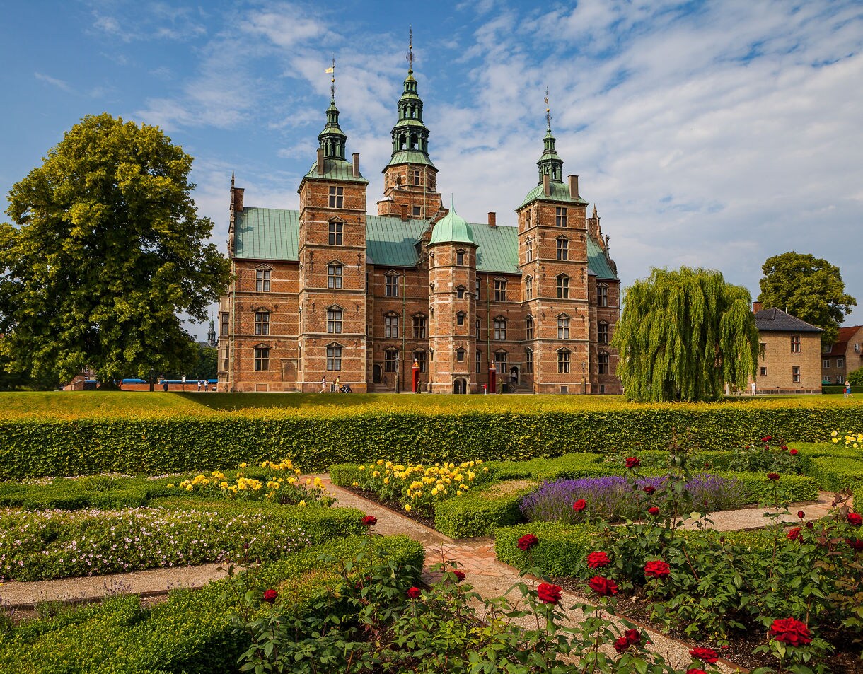 Renaissance-style Rosenborg Castle with copper spires rising behind manicured flower gardens in Copenhagen.