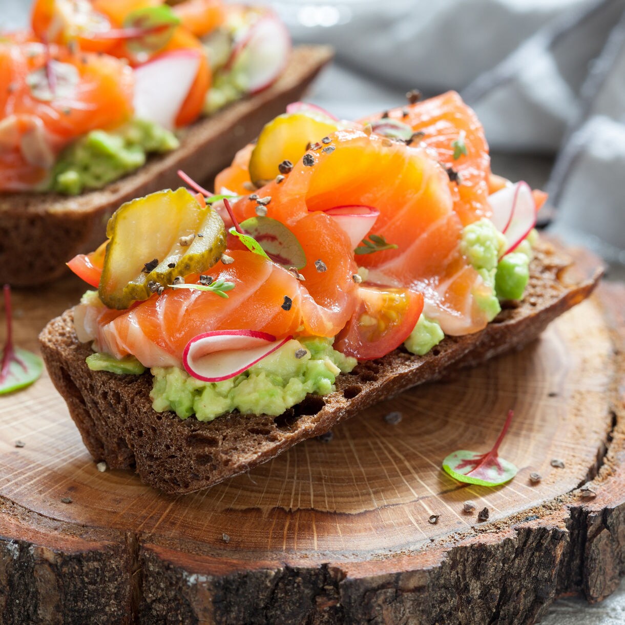 Open-faced Danish sandwich topped with shrimp, dill, lemon, and herbs on dark rye bread.