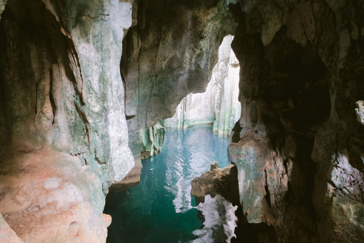 Interior of the Sawa-i-Lau Caves in Fiji with rugged limestone formations and calm turquoise water reflecting soft light.