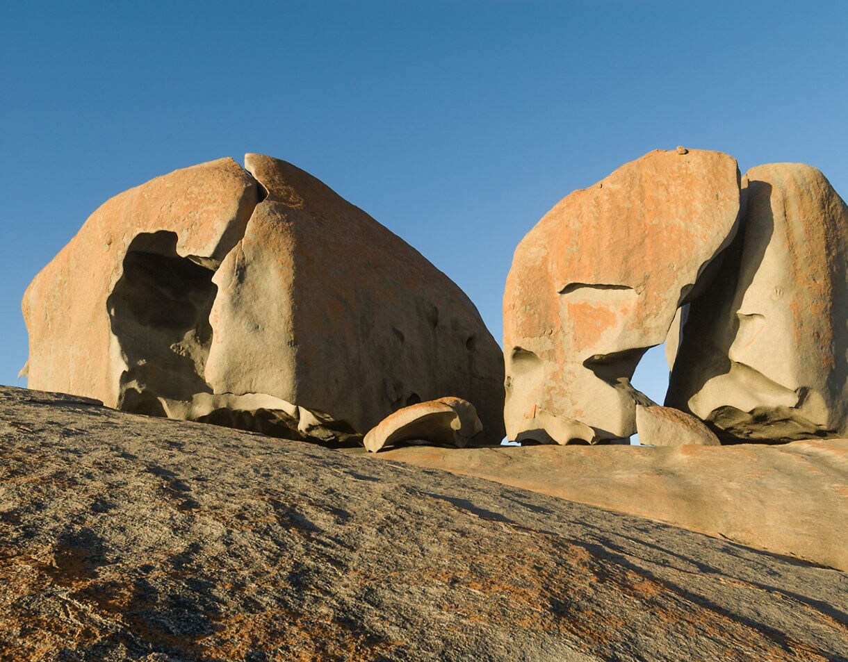 Massive weathered boulders with orange lichen under a clear blue sky in Flinders Chase National Park.