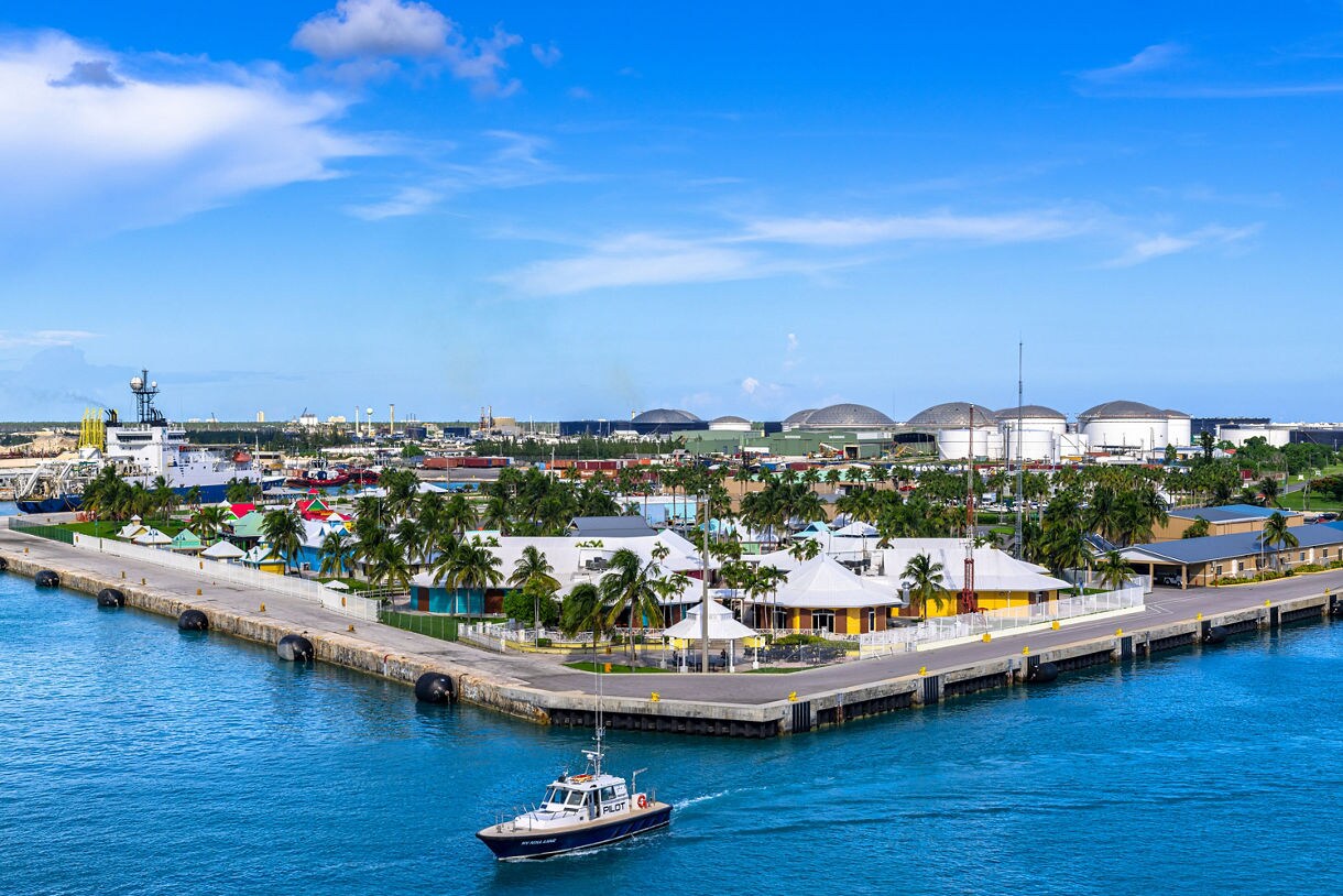 View of Freeport harbor in the Bahamas with colorful buildings, palm trees and ships docked at the port.