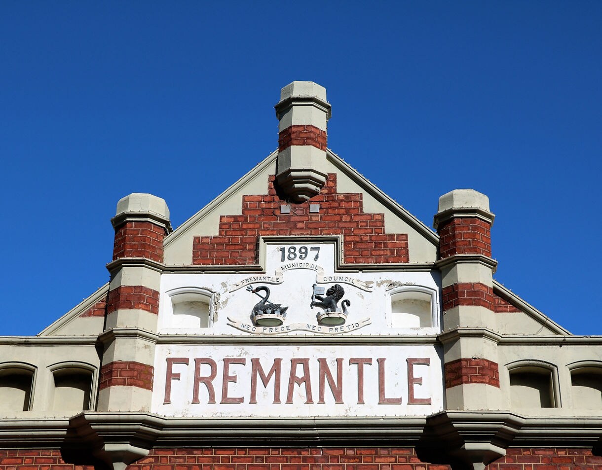 Historic brick facade of Fremantle Markets in Australia with “1897” and “Fremantle” signage under a clear blue sky.