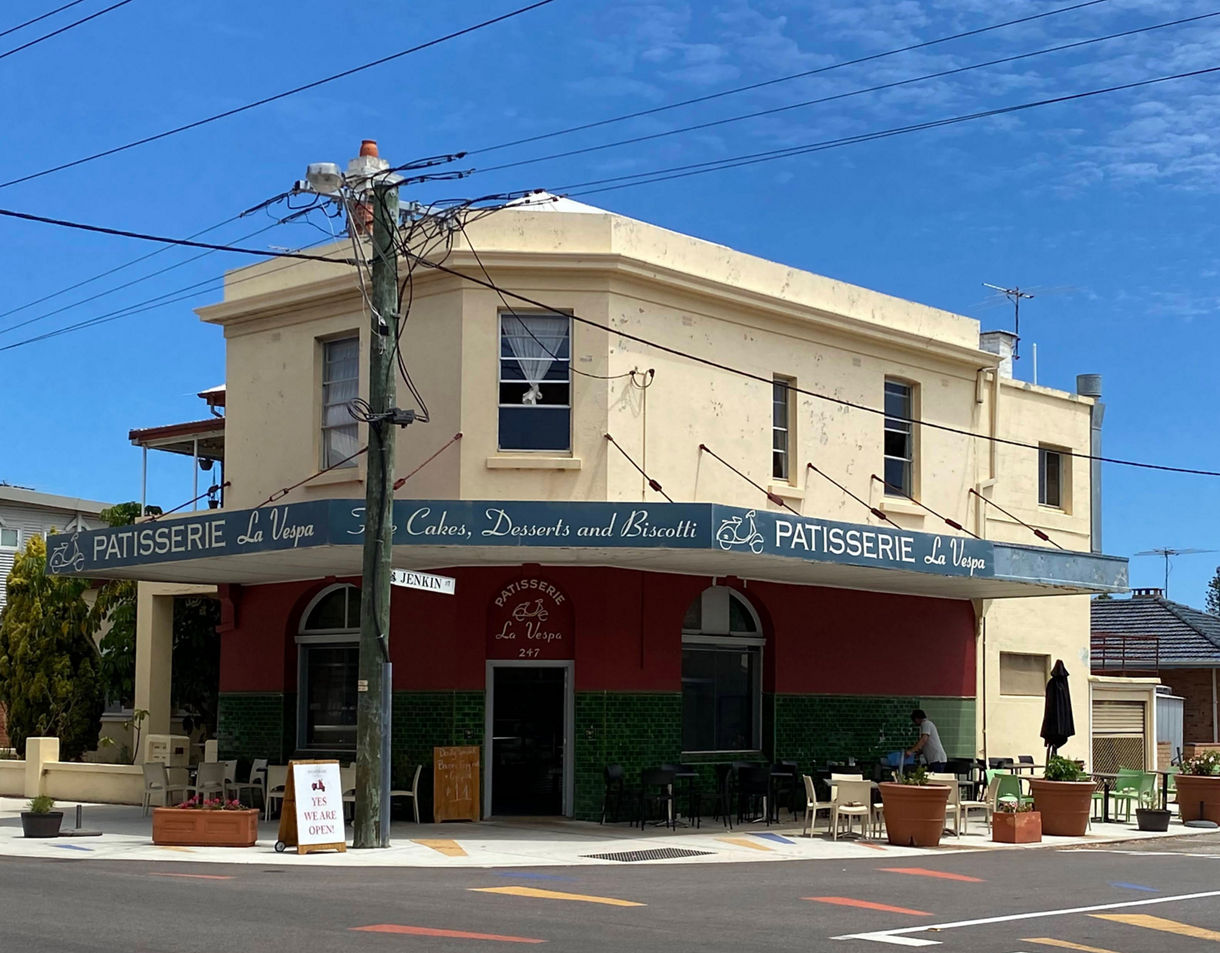 Street view of Patisserie La Vespa in Fremantle, a corner café with outdoor seating, vintage-style signage and potted plants.