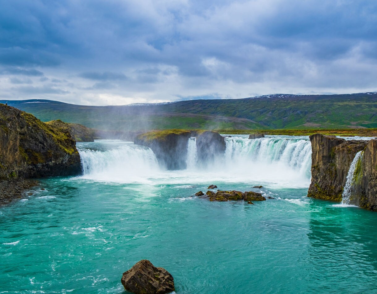 Wide view of Gullfoss waterfall in Iceland, cascading in powerful streams into a turquoise river below.