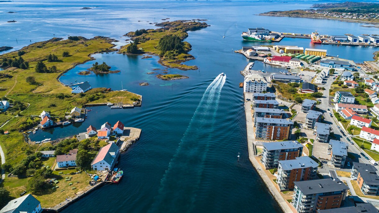Aerial view of Haugesund showing small islands, colorful houses and boats moving through blue coastal waters.