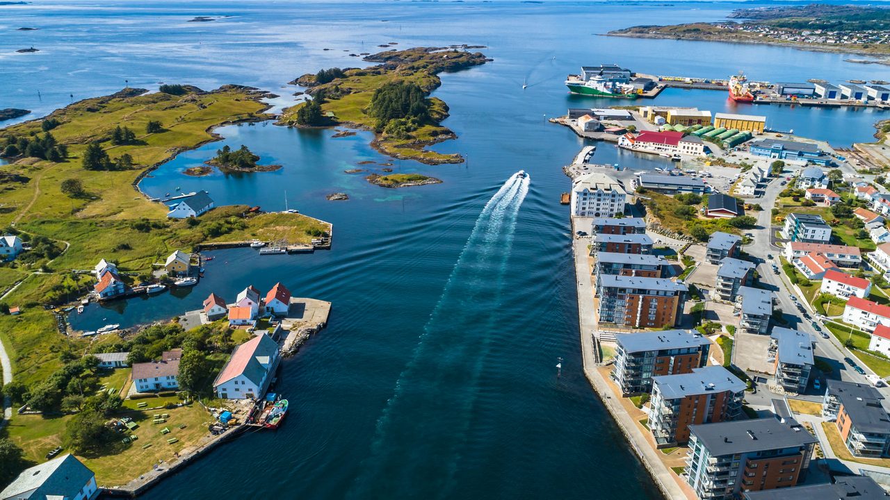 Aerial view of Haugesund showing small islands, colorful houses and boats moving through blue coastal waters.