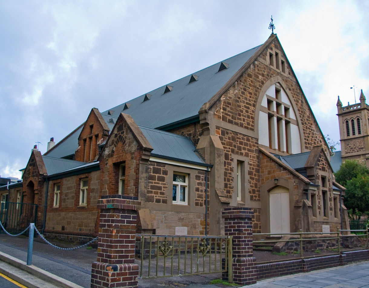 Exterior view of Holy Trinity Church in Adelaide, a historic sandstone building with Gothic-style windows and a tall bell tower.
