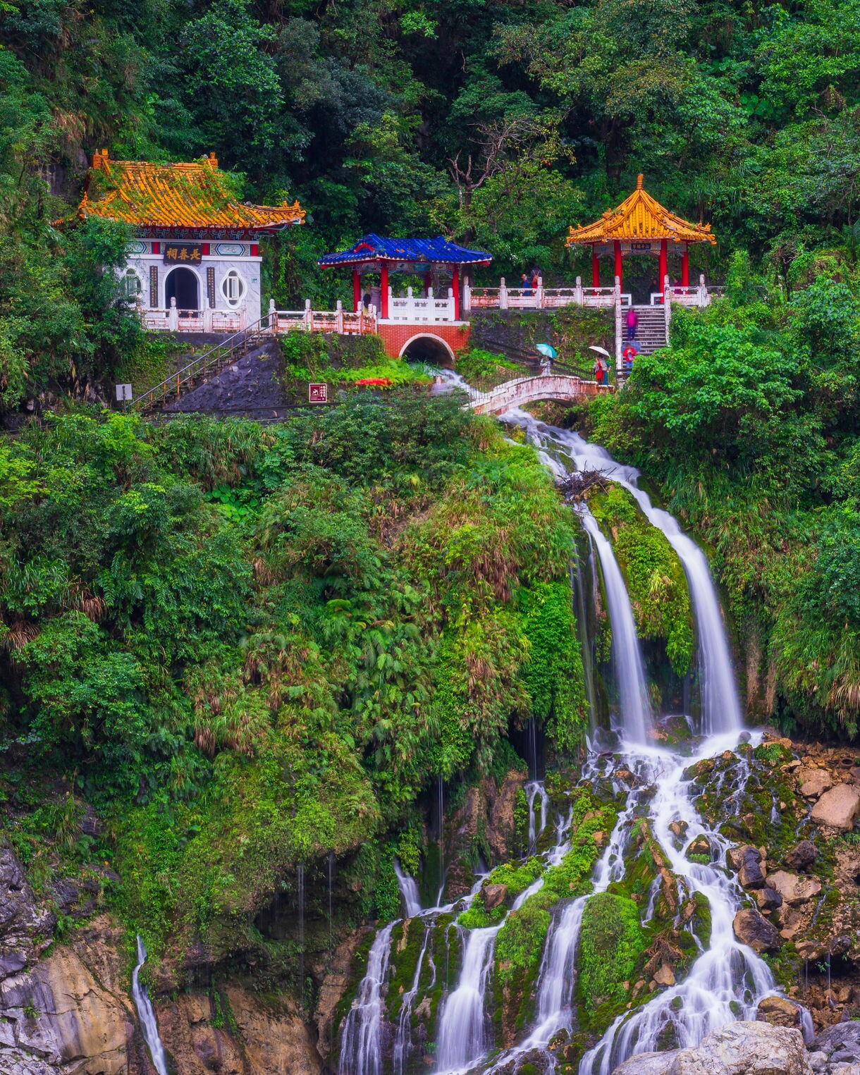 The Eternal Spring Shrine in Hualien, Taiwan, featuring colorful temple pavilions built into a lush mountainside with a waterfall flowing below.