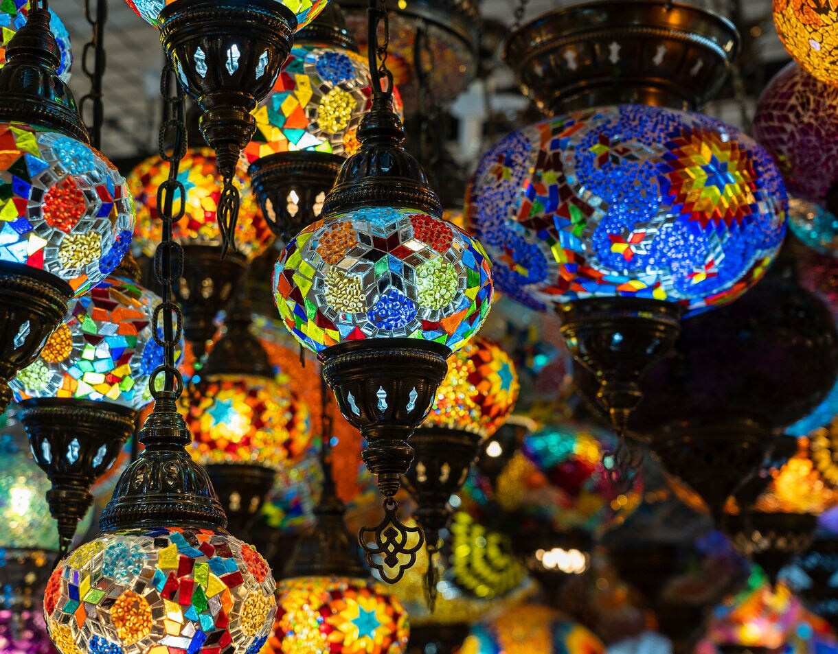 Vibrant Turkish mosaic lamps hanging in clusters at Istanbul’s Grand Bazaar, glowing with multicolored glass patterns.