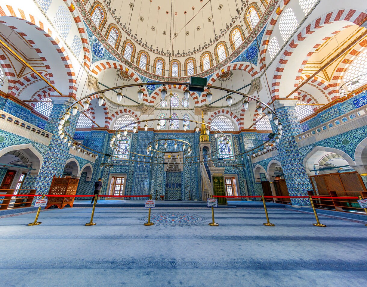 Interior of Rüstem Pasha Mosque in Istanbul, with intricate blue Iznik tiles, patterned arches and a grand central dome.