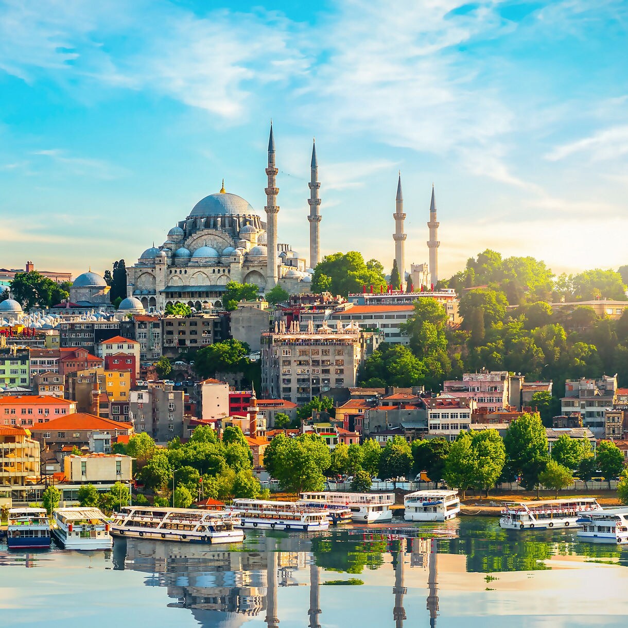 Sweeping view of Istanbul with the domes and minarets of the Süleymaniye Mosque towering over colorful hillside buildings and boats on the Golden Horn.