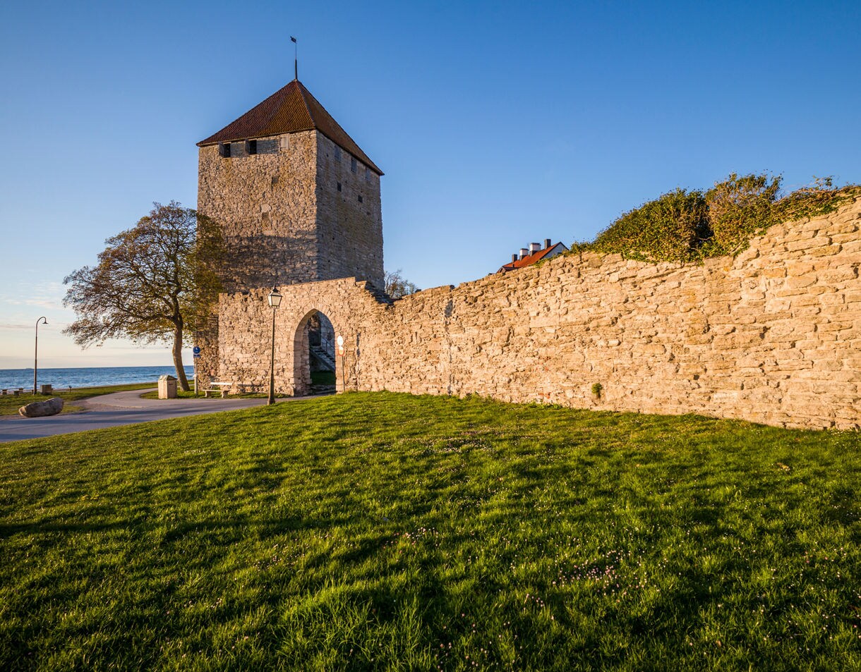 Kruttornet tower in Visby, Gotland, Sweden, a medieval stone fortification with red roof, next to the old city wall and overlooking the sea.