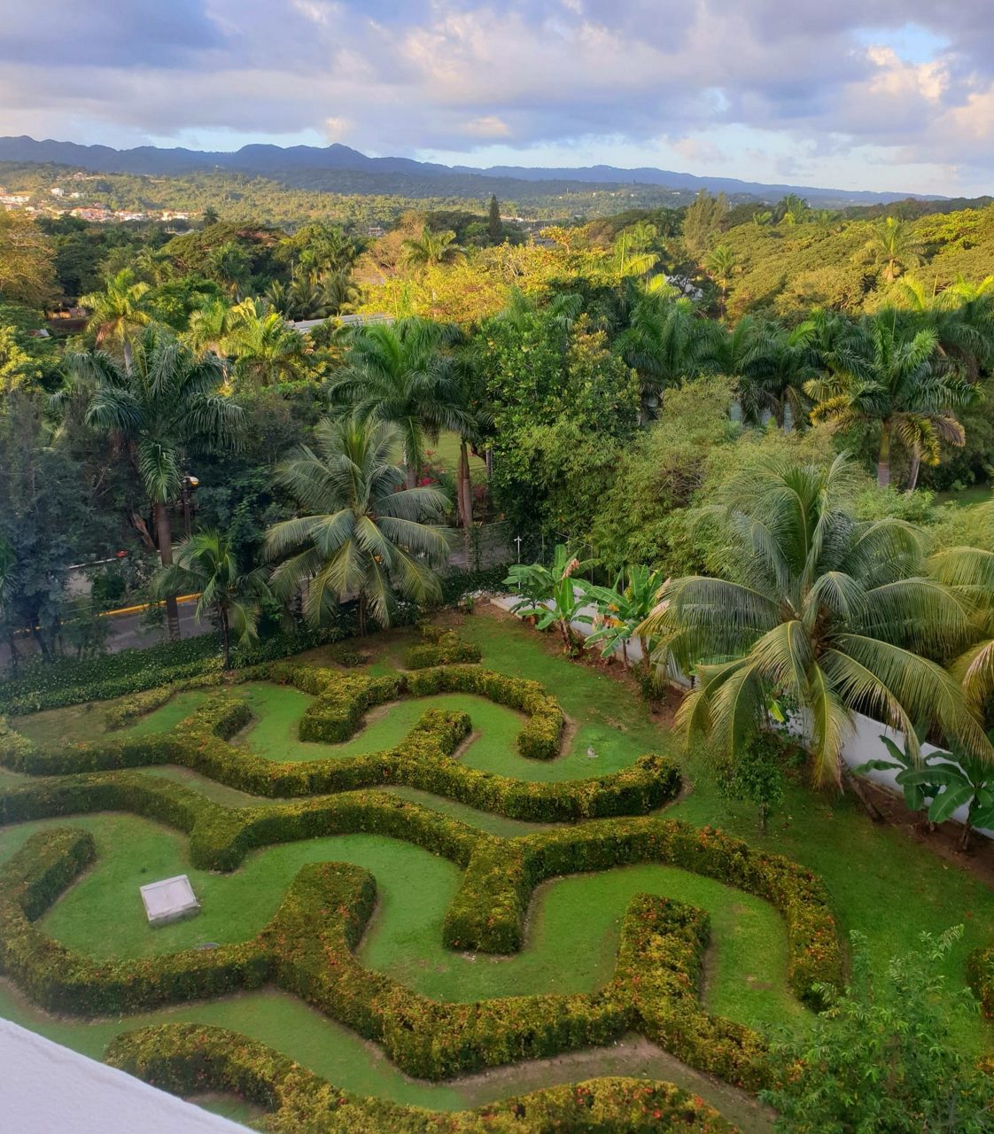  Aerial view of Ocho Rios landscape with a trimmed garden maze, palm trees,and forested hills stretching into the distance.
