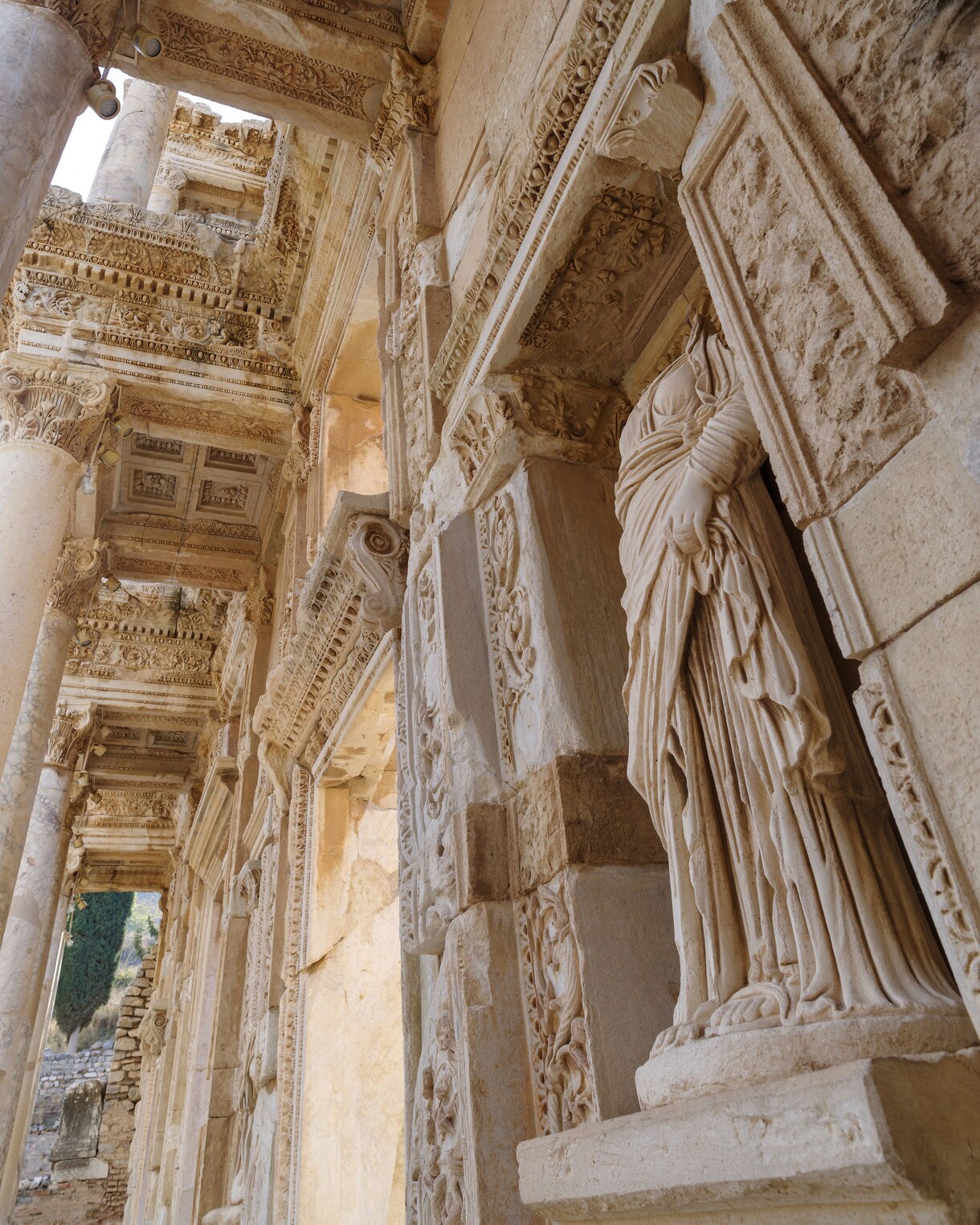Close-up of ornate marble columns and detailed statues on the facade of the Celsus Library in Ephesus, showing carved patterns and architectural reliefs.