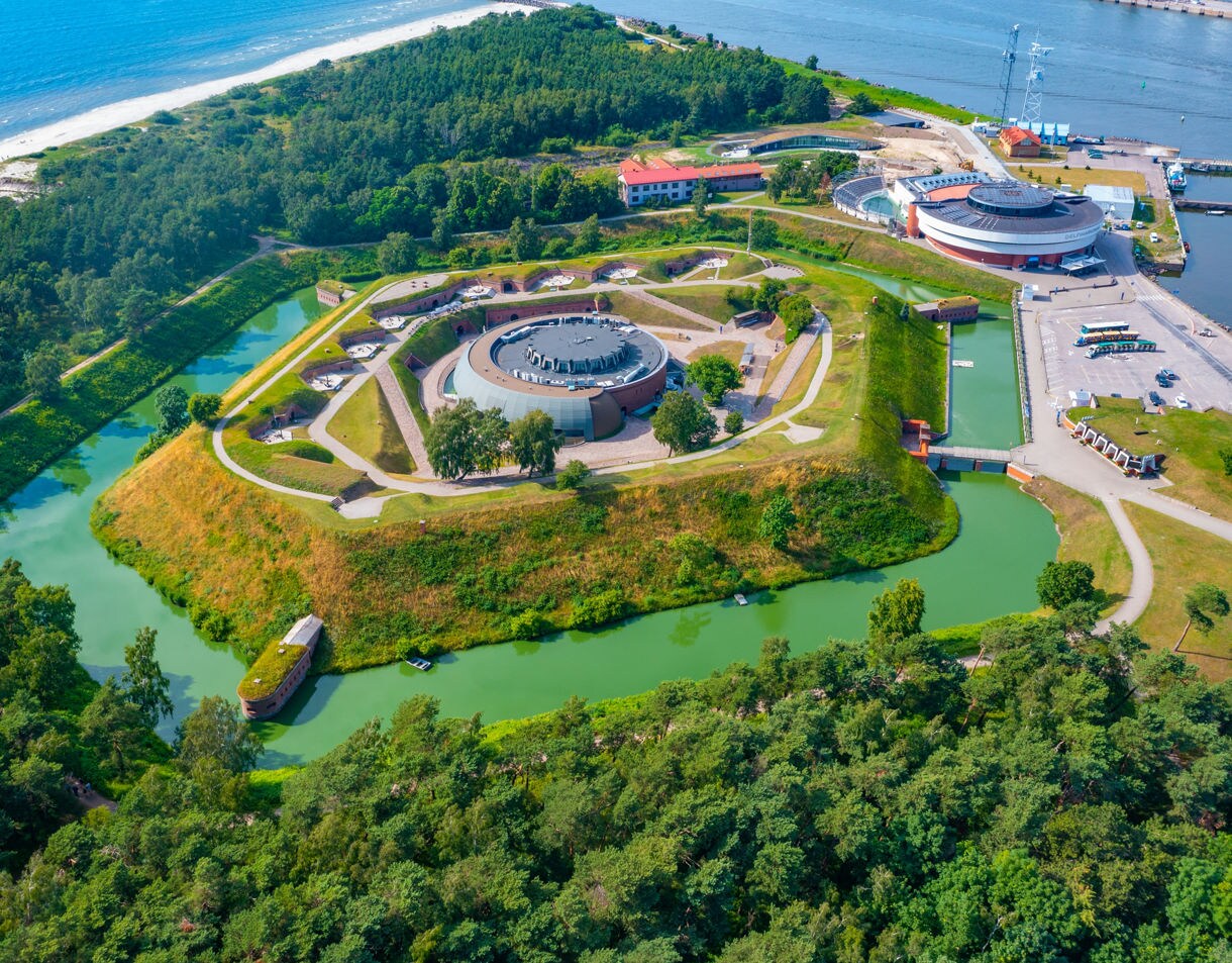 Aerial view of the Lithuanian Sea Museum in Klaipėda, Lithuania, housed in a circular fortress surrounded by green moats and located by the Baltic coast.