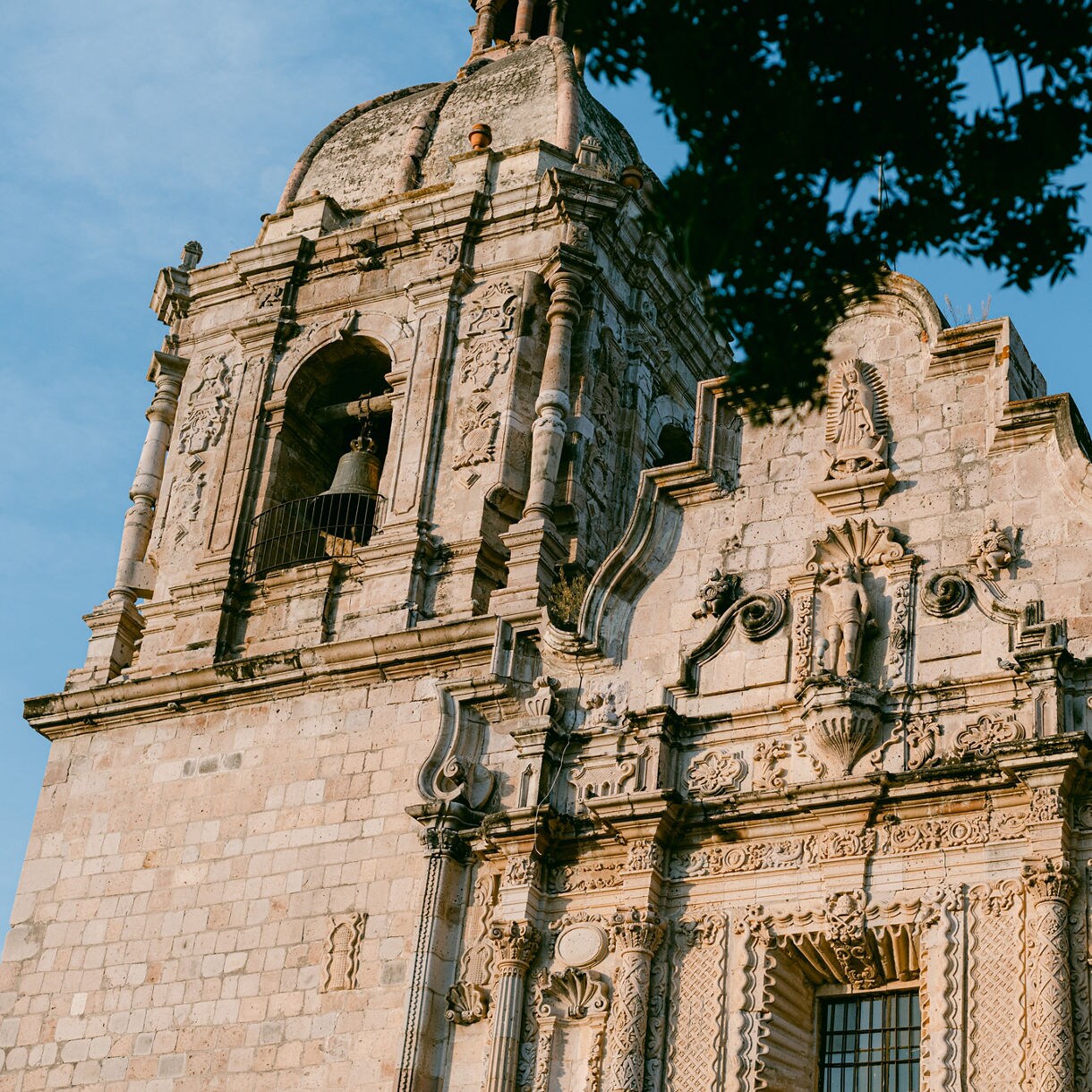 Stone facade of Concordia’s colonial-era church with ornate carvings, statues and a bell tower set against a clear blue sky.