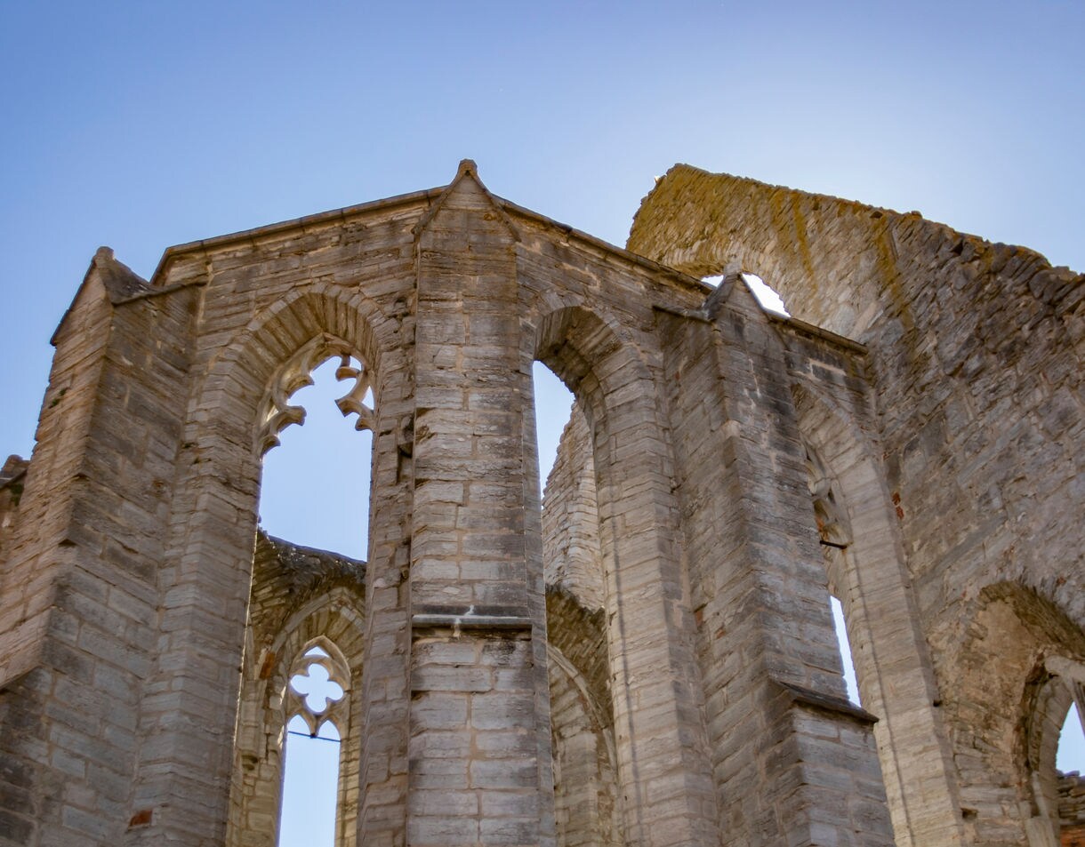 Gothic stone arches of a ruined medieval church in Visby rising against a clear blue sky.