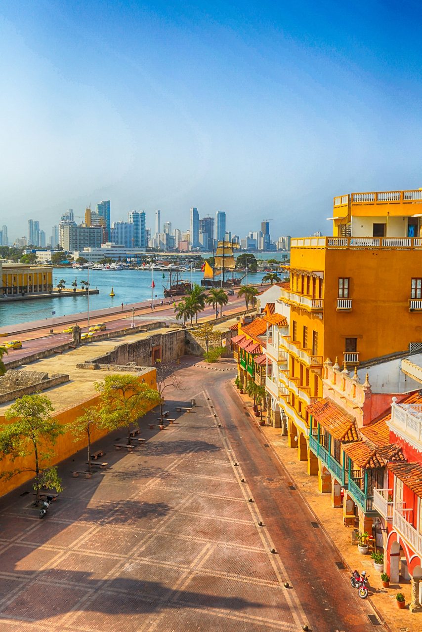 Aerial view of Cartagena’s walled city with colorful colonial buildings in the foreground and a modern skyline across the bay.