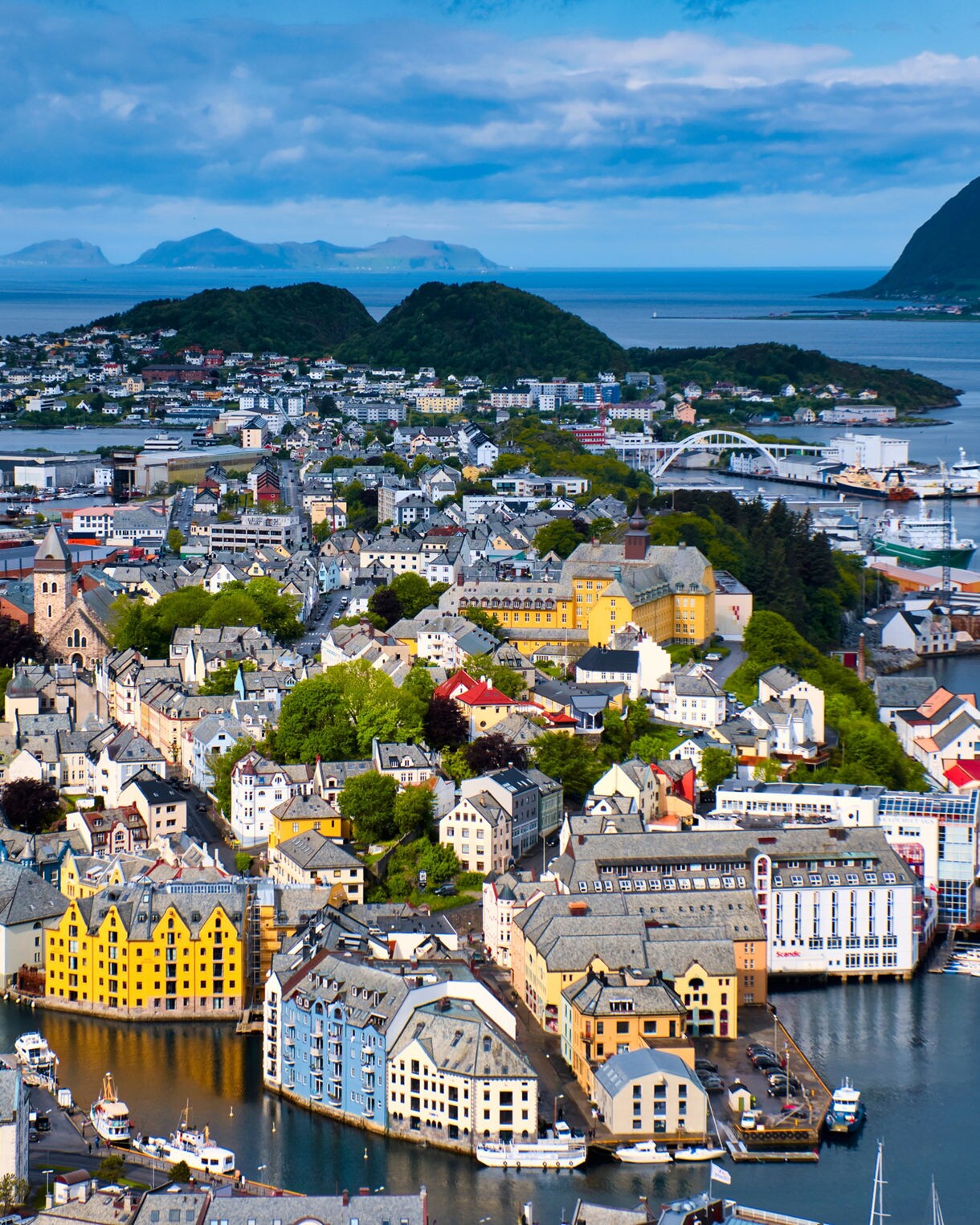 Aerial view of Ålesund from Mount Aksla, showcasing colorful Art Nouveau buildings, winding canals and surrounding fjords.
