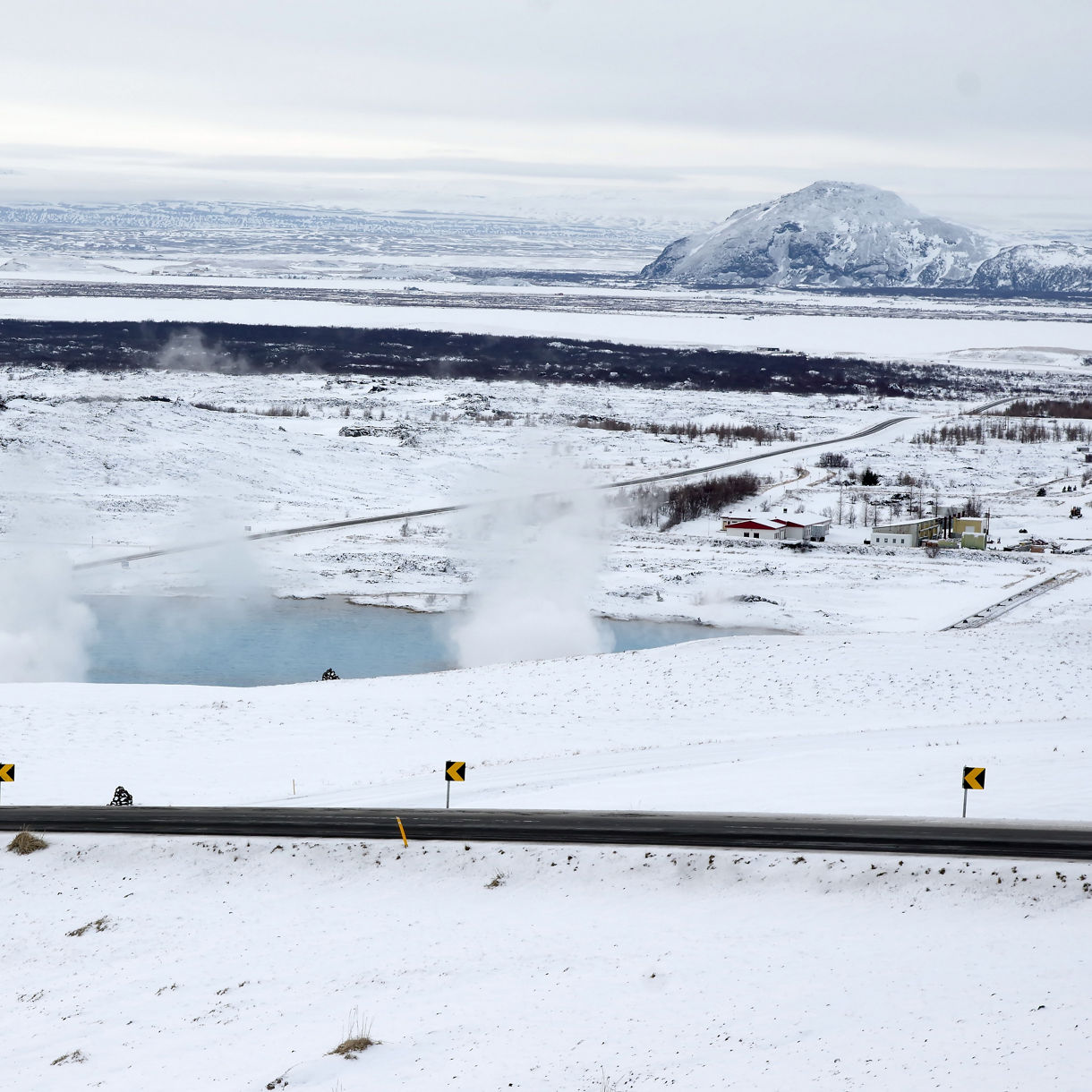 Mývatn Nature Baths in Iceland, with steaming blue geothermal pools surrounded by snow-covered fields and mountains in the distance.