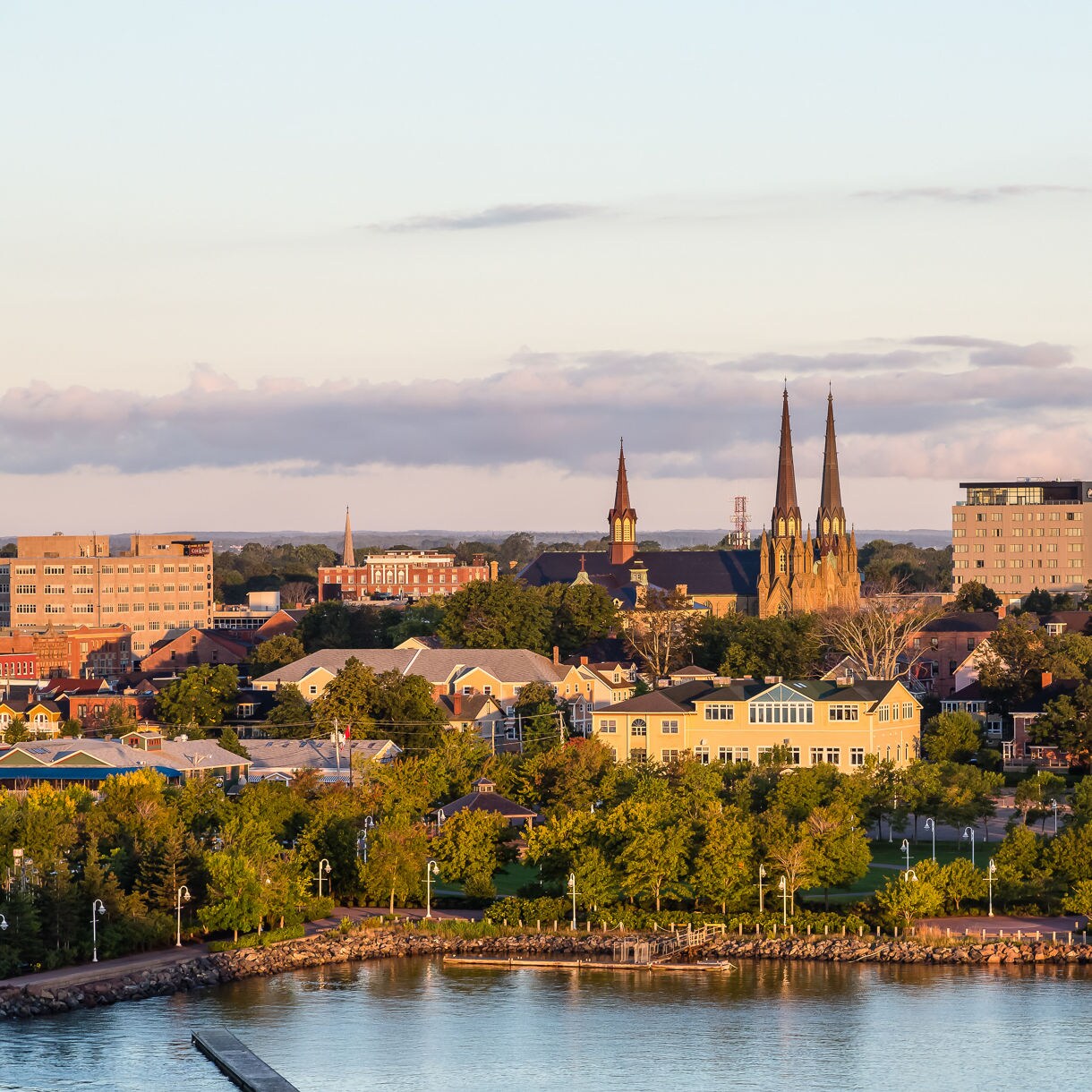 A person walks through a historic stone archway illuminated by warm sunlight. The setting appears to be a coastal fort or castle, with cobblestone flooring and wooden gates. The silhouette of the individual and the golden light create a serene and timeless atmosphere.
