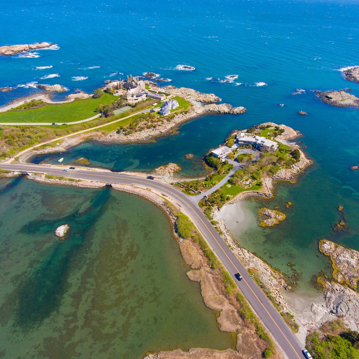 Aerial view of Newport’s Ocean Drive showing winding coastal roads, rocky shorelines and small islands surrounded by bright blue water.