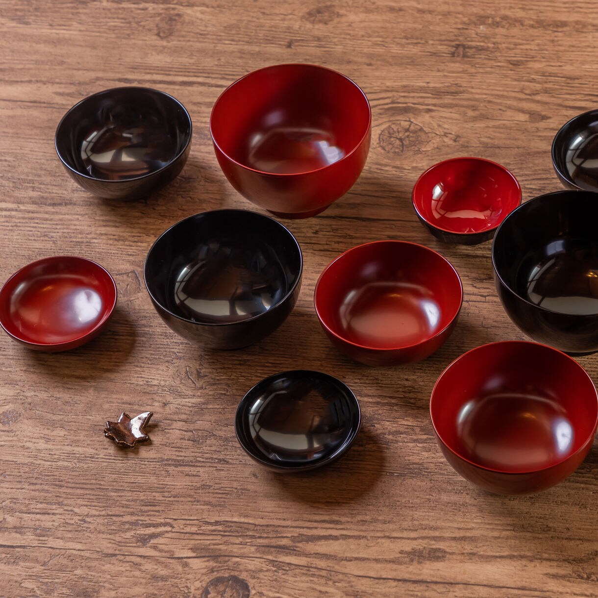 Interior view of a traditional Japanese tatami room with open sliding panels revealing a vibrant garden filled with red, orange and green autumn foliage, stone lanterns and carefully shaped shrubs.