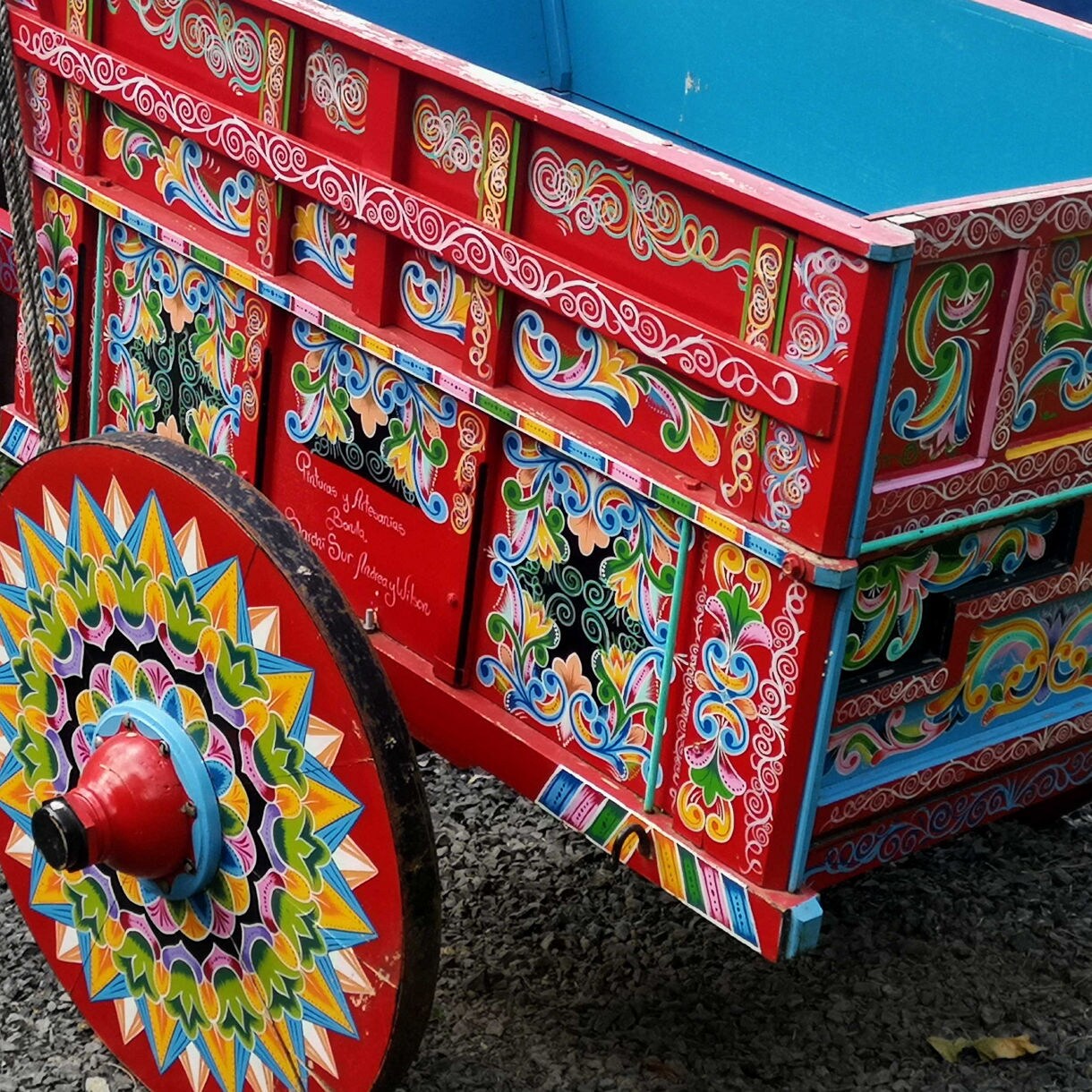 A brightly painted traditional Costa Rican oxcart decorated with colorful floral and geometric patterns.