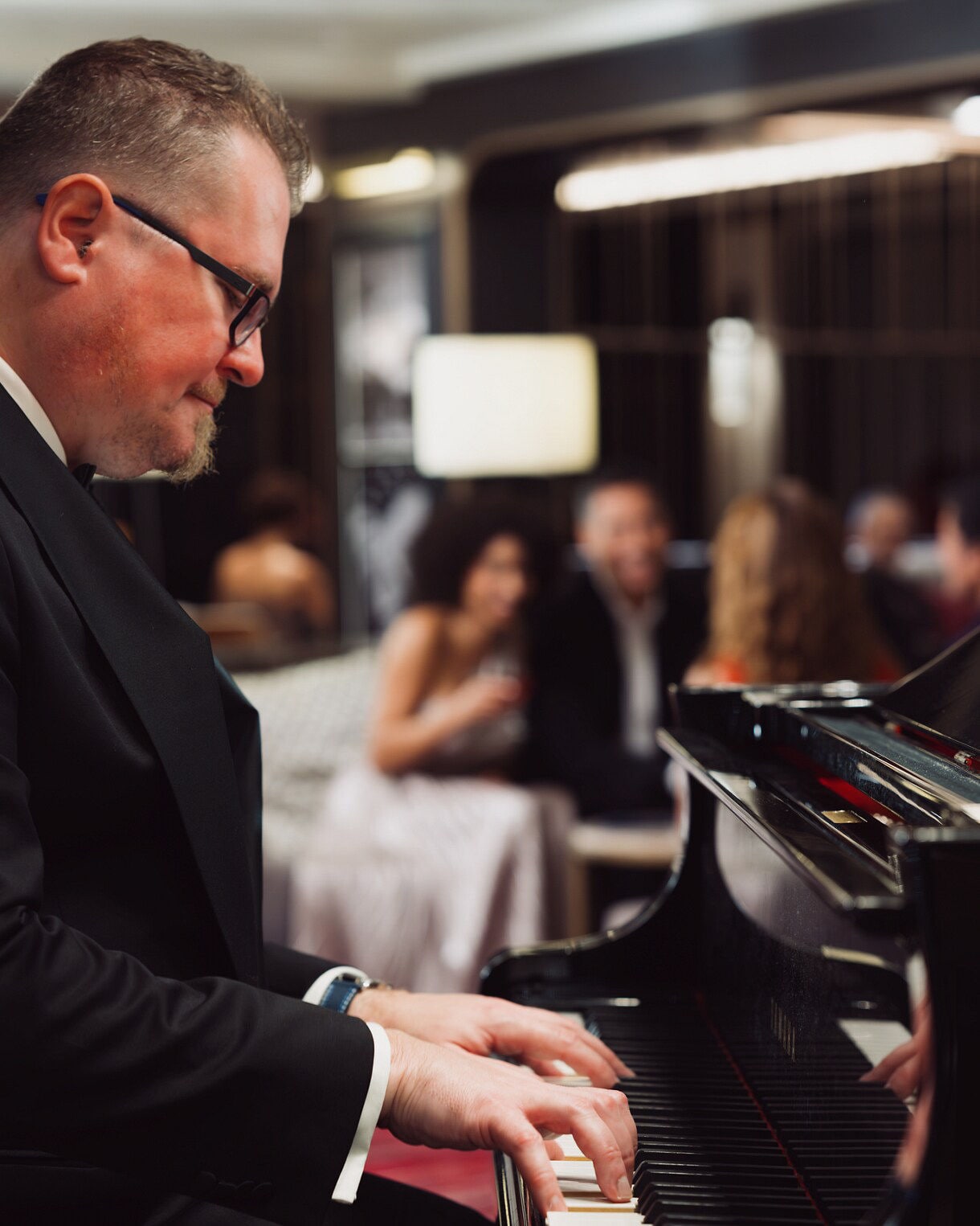  A pianist in formal attire performs on a grand piano in an elegant lounge setting.
