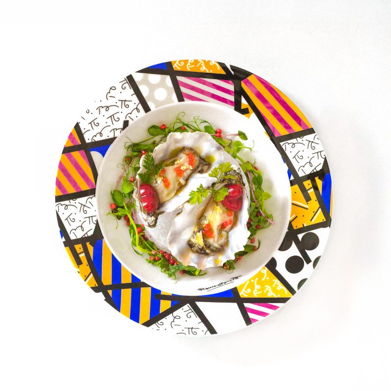 A colorful salad served on a plate decorated with Romero Britto's signature geometric patterns and bright colors. 