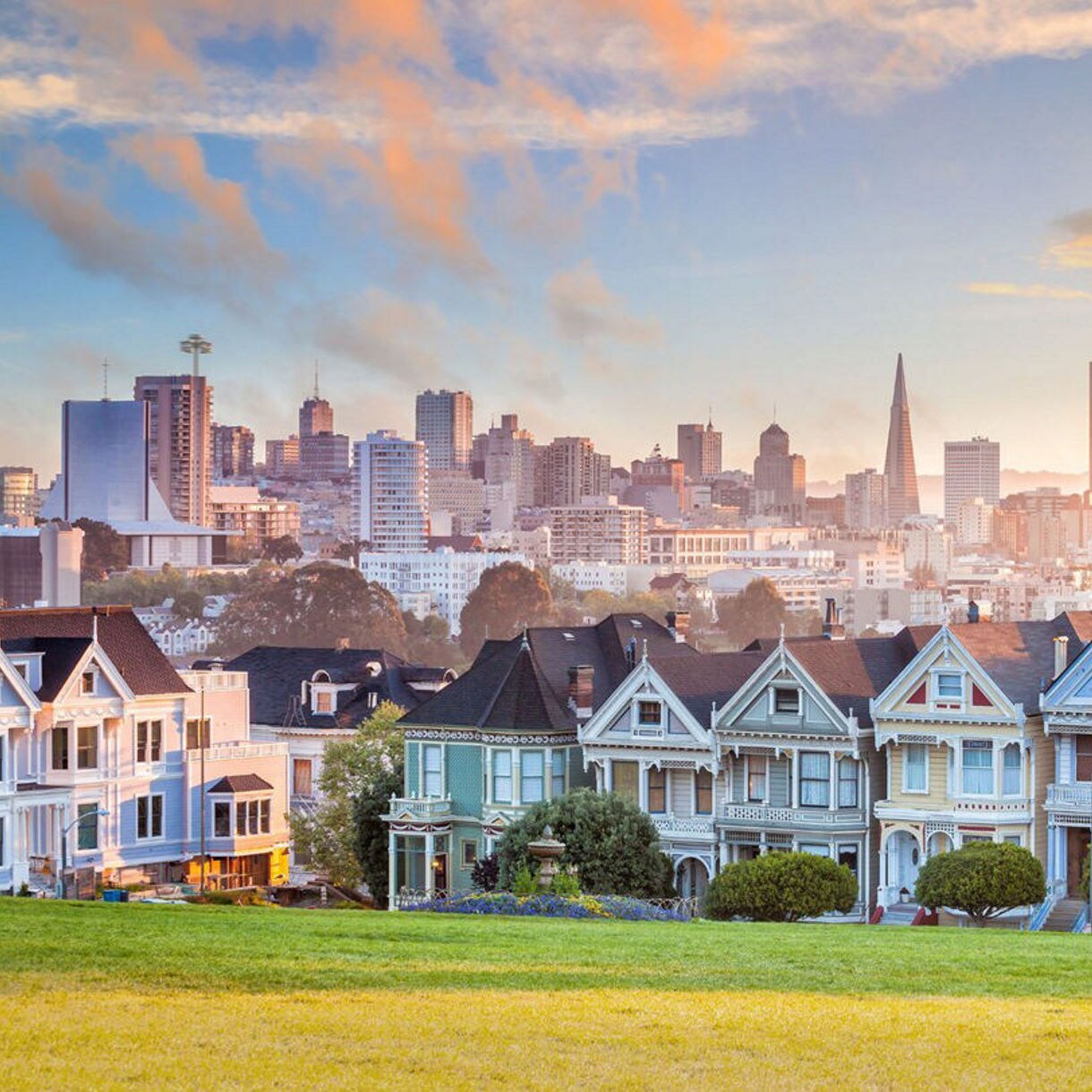 The Painted Ladies Victorian homes with downtown San Francisco's skyline in the distance, lit by the soft morning light.