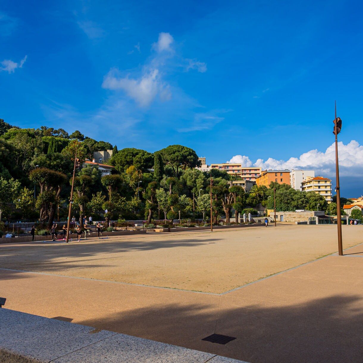 Wide plaza at Place d’Austerlitz in Ajaccio, France, bordered by trees and residential buildings on a bright afternoon.