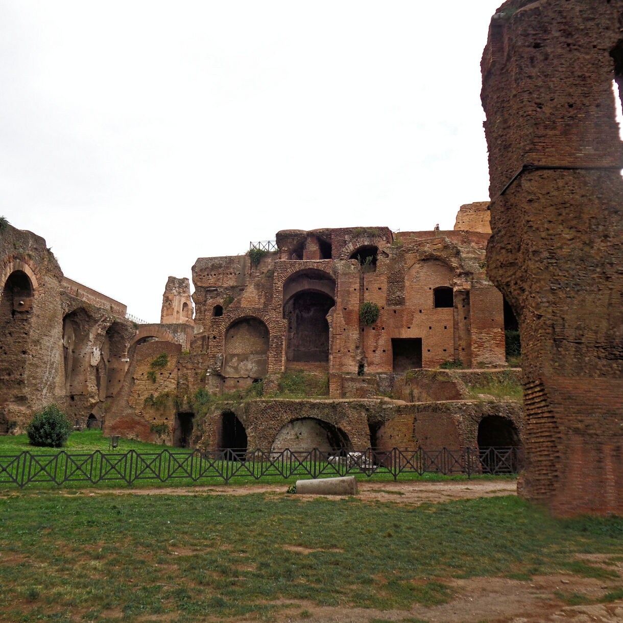 Weathered brick walls and arched passages of Rome’s catacombs, with grassy grounds and remnants of underground structures.